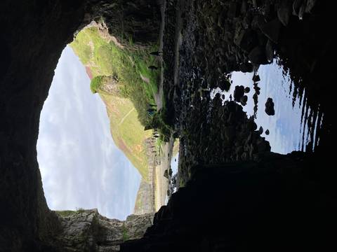Cave opening looking out to a rocky beach and cliffs.