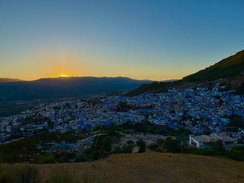       Hilltop view of a blue city during sunset.
  