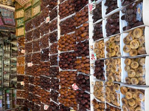       Image of a market stall with various types of dates and dried fruits displayed in white boxes.
  