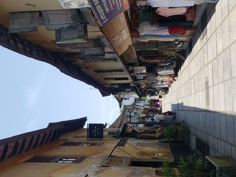 A narrow street lined with shops and a few people walking.