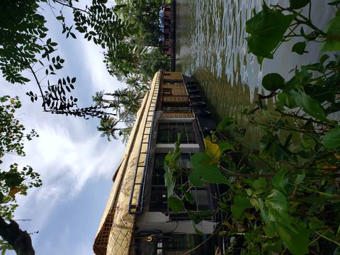 A traditional Indian houseboat on the water surrounded by lush greenery.