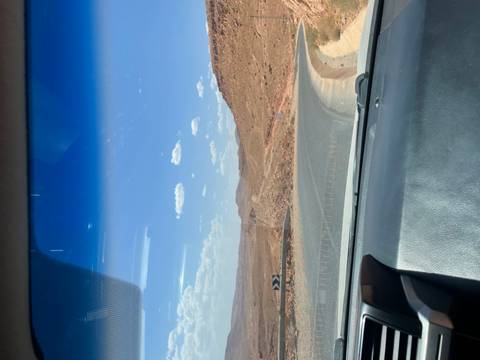 View from a car of a winding road through a barren desert landscape.