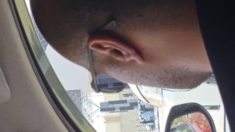 Person's head and partial view of a car with a street scene outside.