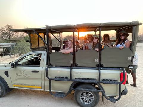 Safari vehicle with tourists during sunset.