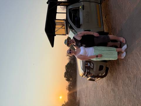 Couple standing near a safari vehicle at sunset.