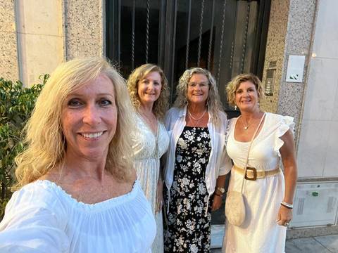Four women posing for a selfie in a city.