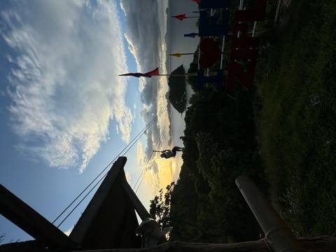 Person zip-lining with ocean view at sunset.
