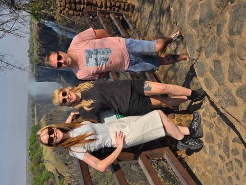 Three people posing near a waterfall.