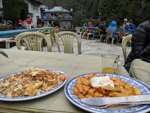 Plates of food on an outdoor table with people in the background.