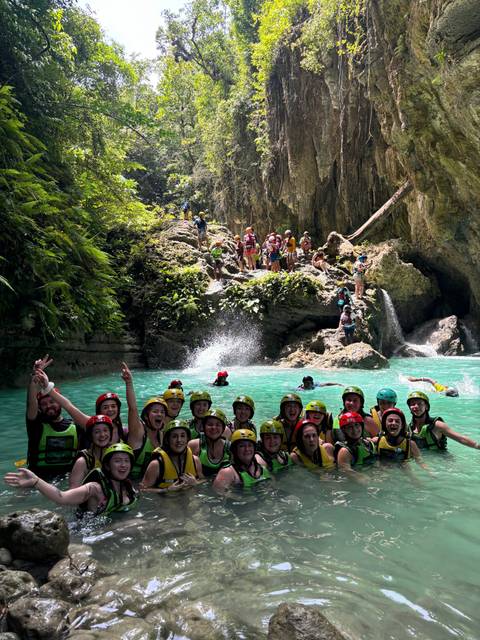       Group of people swimming near a waterfall.
  