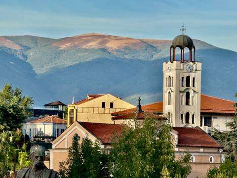 A historical tower with mountains in the background.