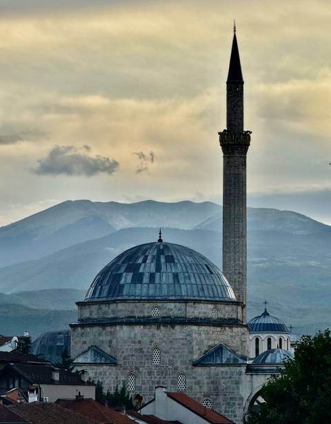 Dome and minaret against a backdrop of mountains.