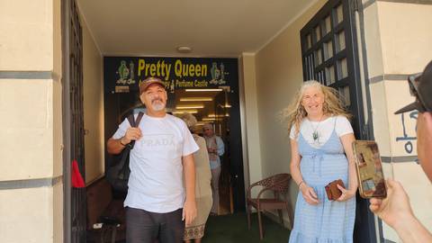 People outside a shop sign reads 'Pretty Queen' in English.