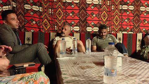 Group of people sitting inside with colorful patterned walls.