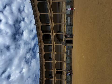       Historical bullring with people walking.
  