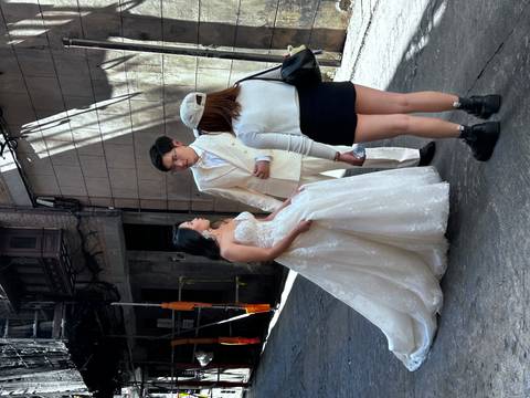      Bride and groom with a photographer in a narrow street.
  