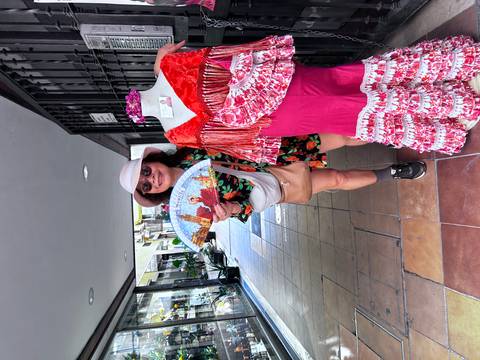       Woman posing with a colorful fan and mannequin wearing a flamenco dress.
  