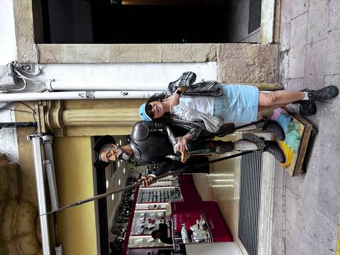       Woman posing with a statue of Don Quixote outside a shop.
  