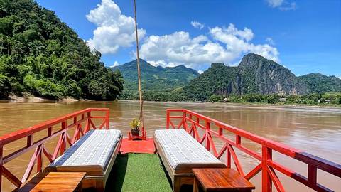 View from a boat on a river with mountains and clear sky.