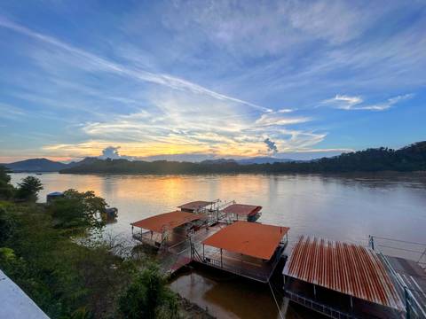       Sunset over a river with mountains and boats.
  