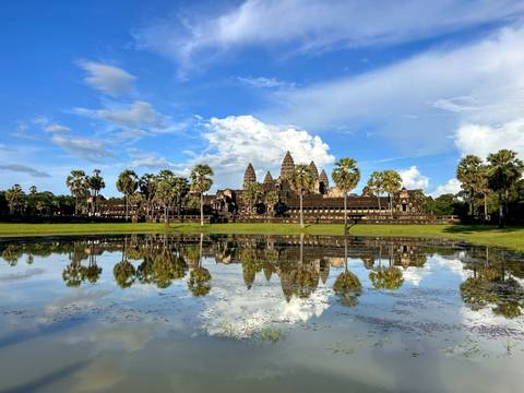 Angkor Wat temple reflecting in water under a vibrant sky.