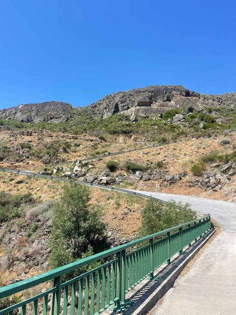 Winding road ascending a rocky hillside.