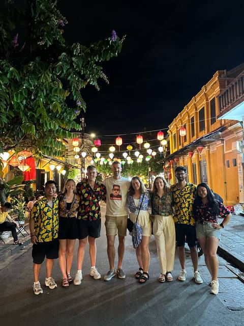 A group of people posing at night under lanterns in a colorful street.