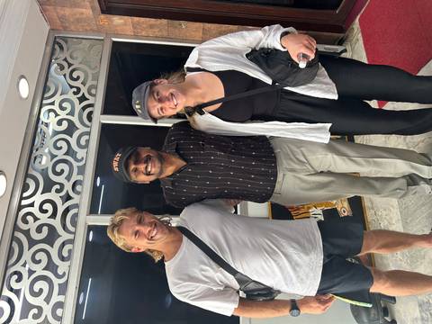       Three people posing together indoors.
  