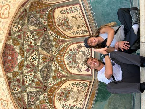       Two people posing under a decorated ceiling.
  