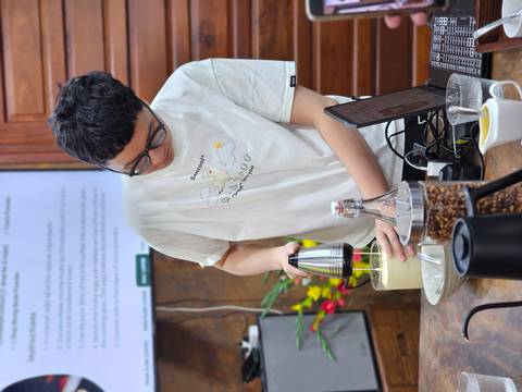 Person preparing egg coffee with electric frother.