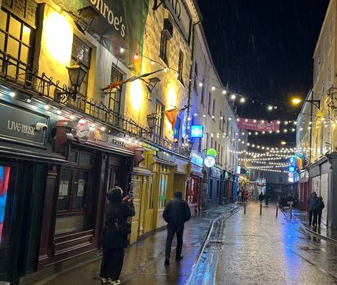      Cobbled street lined with colorful buildings and lights.
  