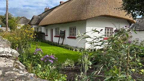       Traditional thatched-roof cottage with garden.
  