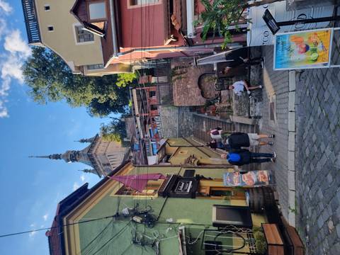       Colorful old town street with shops and people.
  