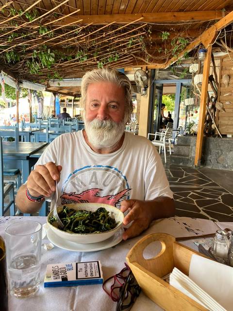       Man enjoying a meal in a rustic outdoor restaurant.
  
