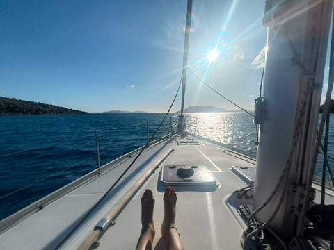       View from a sailboat's bow towards the sea and mountains.
  