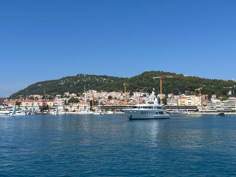 A coastal town with boats in the harbor and hills in the background.