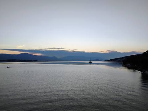 A calm sea with distant islands and a sunset or sunrise sky.