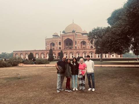 Group of people posing in front of Humayun's Tomb on a cloudy day.