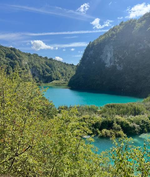 Turquoise lake surrounded by forested hills.