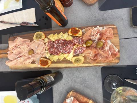 Charcuterie board with various meats, cheese, and olives.