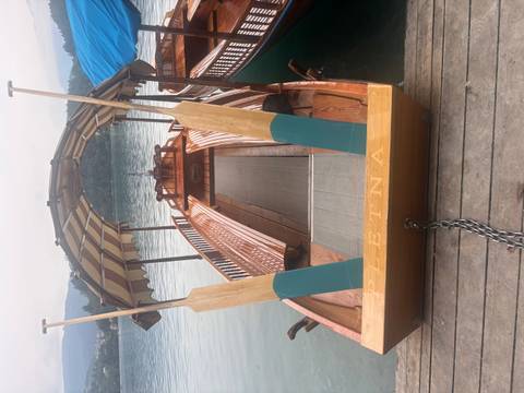Traditional wooden boat docked by a lake.