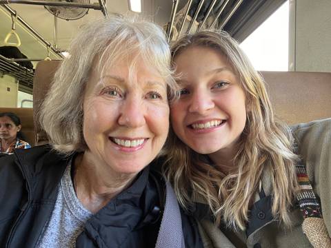 Close-up of two smiling people on a train.