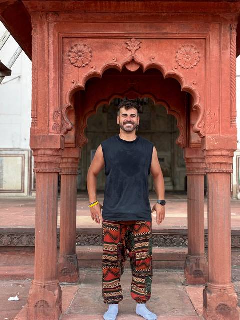       A man standing in front of a red architectural structure.
  