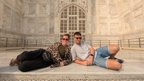 Couple posing while lying in front of the Taj Mahal.
