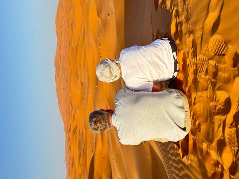 Two people sitting and enjoying a view of the desert dunes.