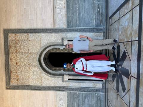 Tourist posing with a traditional guard at a formal building.
