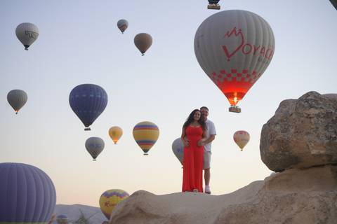       Couple with hot air balloons in the background at sunrise.
  