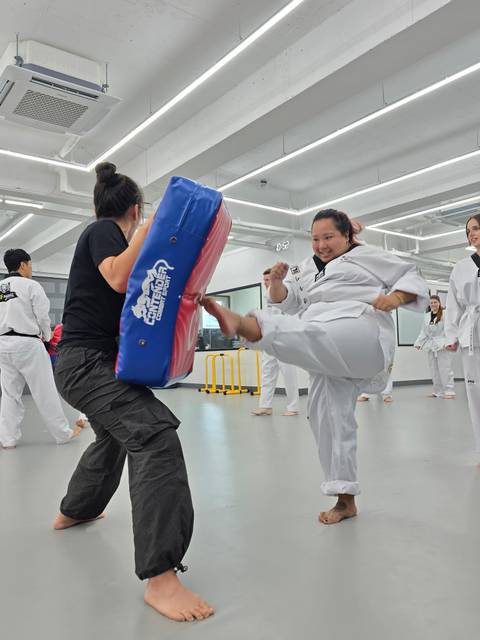 Taekwondo class with students practicing kicks.