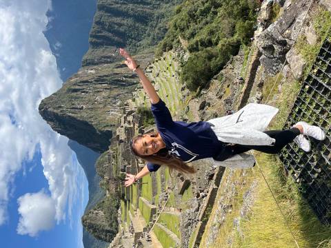 Woman celebrating with open arms at Machu Picchu against a backdrop of the ancient ruins.