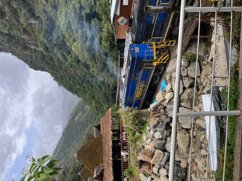       Train with PeruRail branding surrounded by lush mountains.
  